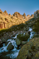 High alpine mountain river going through the valley in corsica mountains lit by the evening sun GR20