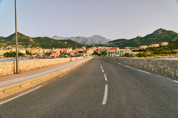 Road to Ille Rouse harbour city in Corsica Corse France with high alpine mountains in the background