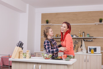 Mother hugging her litthe daughter and preparing salade. Mother love.