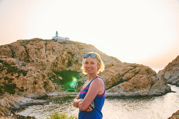 Blonde happy smiling tourist girl under the Pietra lighthouse in Corsica