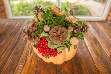 Pumpkin, viburnum, cones, nuts, acorns, chestnuts on a wooden background. Autumn composition by own hands