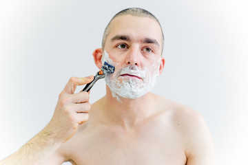 man is shaving his face in a bathroom