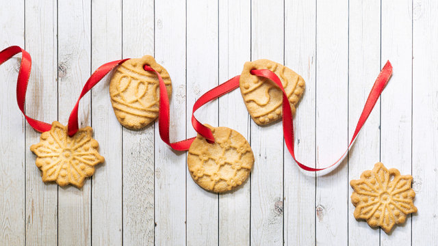 Christmas cookies threaded on red ribbon.