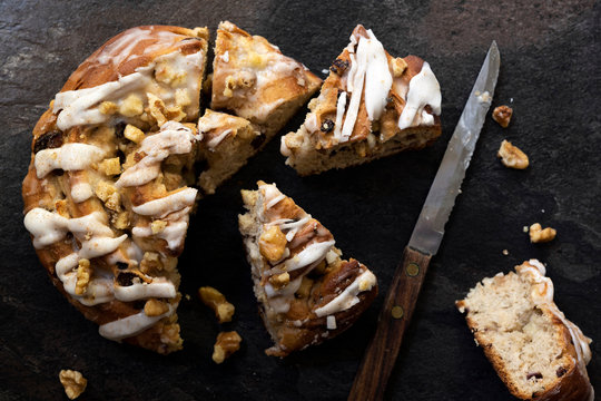 Apple, walnut and cinnamon bun cut into pieces with a knife.