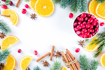 Winter autumn drink and food ingredients. Cranberries, sliced oranges, cinnamon, rosemary, anise for cooking cocktails, with christmas tree branches. Flatlay on white background. Top view copy space