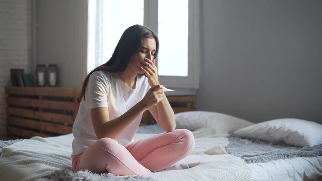sad woman looking on pregnancy test unexpected cries