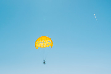 Yellow parachute canopy in a blue sky on a sunny day - parasailing