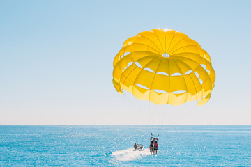 Fun pastime at sea - parasailing with people tied to a boat - Powered by Adobe