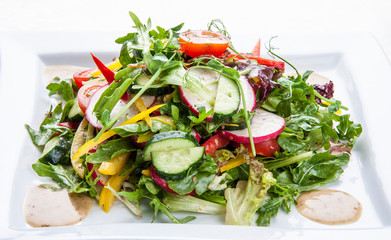 Salad with fresh spring vegetables on a white background.