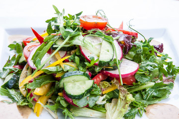 Salad with fresh spring vegetables on a white background.