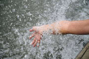 female hand touching water in the river when traveling by boat, splash on boat