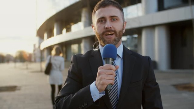 Medium shot of male Caucasian news reporter with reportage from the scene