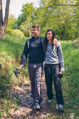 Couple of hikers walking embraced holding trekking sticks outdoors