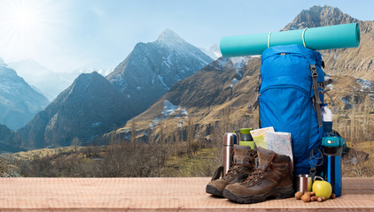 Fototapeta Big backpack and trekking boots with camping equipment, snowy mountains in the background obraz