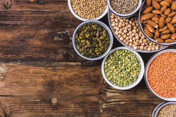 Composition of different types of legumes in bowls on wooden background