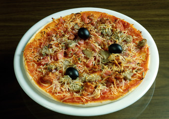 Pizza con tomate, chopiñones, jamón cocido, queso y aceitunas negras.