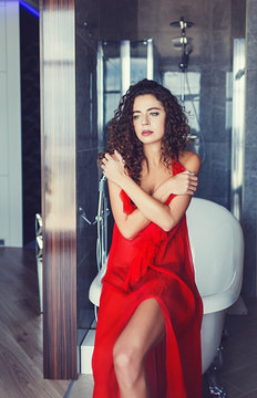 Beautiful curly model in red dress posing indoor