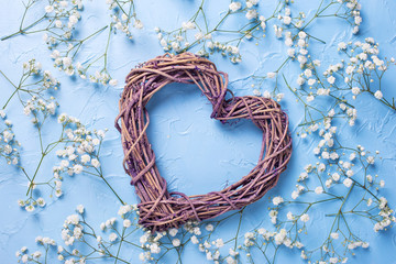 Big decorative heart and p attern from fresh white gypsofila  flowers on blue textured background.