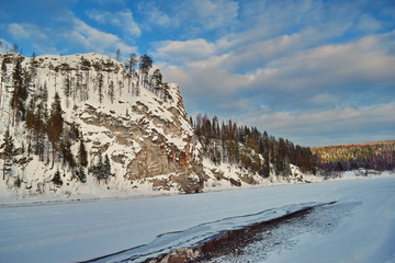 Snow-covered rock on the river Bank