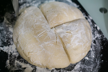 Sliced dough in flour on black breadboard 