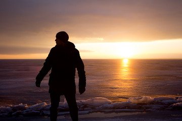 Man on rock on the sea in the ice - silhouette