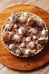 Chestnut Tart with Crumble Topping, decorated with chocolate discs, on wooden board and wooden table.
