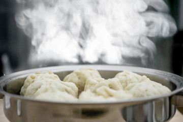 Chinese dumplings (buns) being steamed on a modern stainless steel wok pan