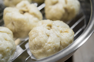 Chinese dumplings (buns) being steamed on a modern stainless steel wok pan