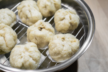 Chinese dumplings (buns) being steamed on a modern stainless steel wok pan