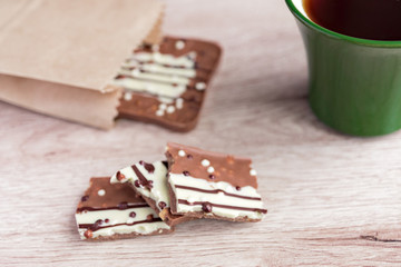 Green cup of americano and milk chocolate bar on wooden background