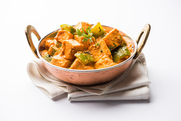 Malai or achari Paneer in a gravy made using red gravy and green capsicum. served in a bowl. selective focus