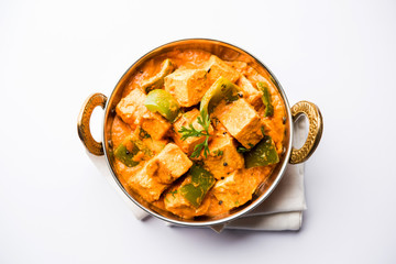 Malai or achari Paneer in a gravy made using red gravy and green capsicum. served in a bowl. selective focus