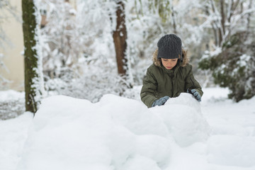 Fototapeta na wymiar boy making snowballs outdoor in snow