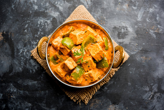 Malai or achari Paneer in a gravy made using red gravy and green capsicum. served in a bowl. selective focus