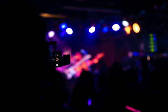 Silhouette of hands using smart phone to take pictures and videos at live concert; Smartphone records live music; Take photo in front concert stage