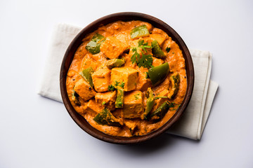 Malai or achari Paneer in a gravy made using red gravy and green capsicum. served in a bowl....