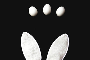 Bunny ears and eggs on a black background.