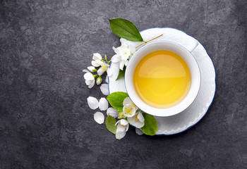 Jasmine flowers and cup of healthy tea, herbal medicine. A cup of green tea with jasmine on a black  background