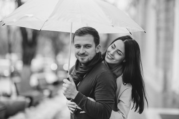 Happy romantic couple, guy and his girlfriend dressed in casual clothes are hugging under the...