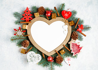 Fototapeta na wymiar Christmas frame in the shape of a heart is surrounded by branches of a New Year tree Christmas decorations with copy space. Top view, flat lay. Nature New Year concept.