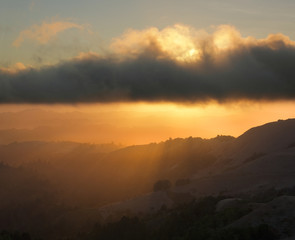 Rays shining on coastal hills at sunset, in California