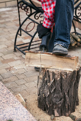 man in plaid shirt is sawing  log on stumpт  electric saw
