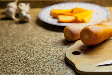 Ripe red carrot and knife lying on wooden board