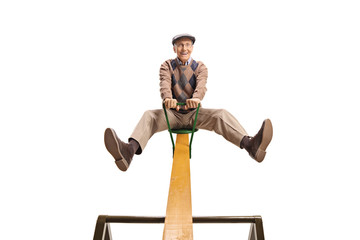 Senior man on a seesaw with his legs up