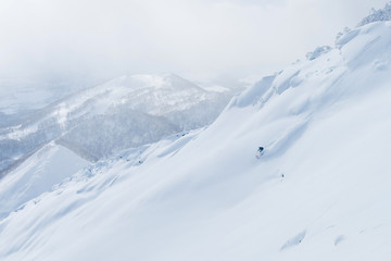 AERIAL: Man shredding the snowy mountain terrain while on fun ski trip in Japan.