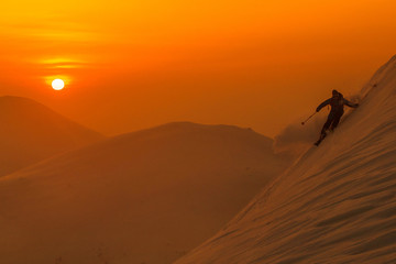 Fototapeta na wymiar SILHOUETTE: Spectacular shot of pro skier riding off trail on a sunny evening.
