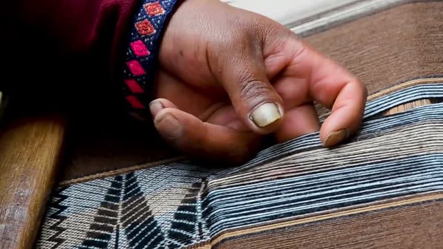 Close up of a man hands weaving on a loom as his ancestors used to do