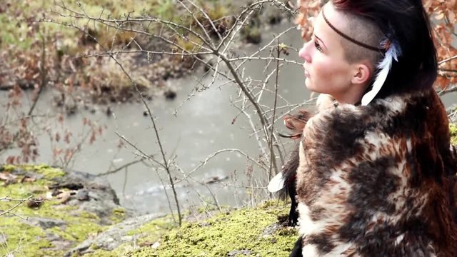 Beautyful viking woman seated on a rock in autumn nature landscape