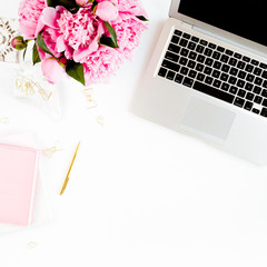 Flat lay women's office desk. Female workspace with laptop, pink peonies bouquet, accessories on...
