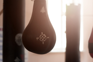 Boxing sand black pearshaped punching bag hanging at a sports gym. A punching bag for boxing with a target logo on it on the background of boxing bags